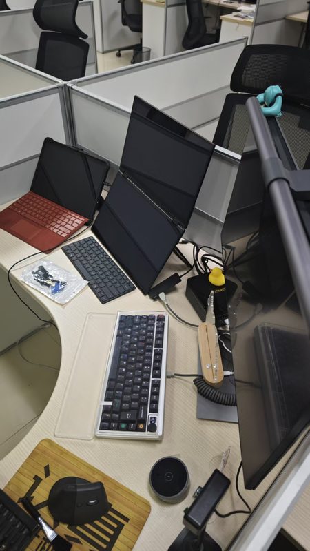 Office cubicle desk with a folded dual-screen portable monitor