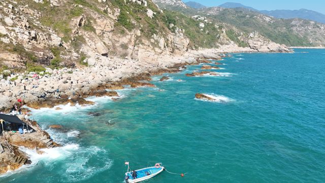 Small boat anchored off a rocky coastline
