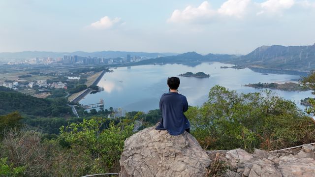 Person sitting on a rock overlooking a reservoir